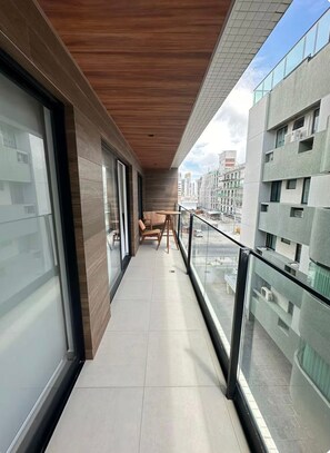 Ein Balkon mit Holzboden, einem Tisch und Stühlen mit Blick auf eine Stadtlandschaft mit modernen Gebäuden.