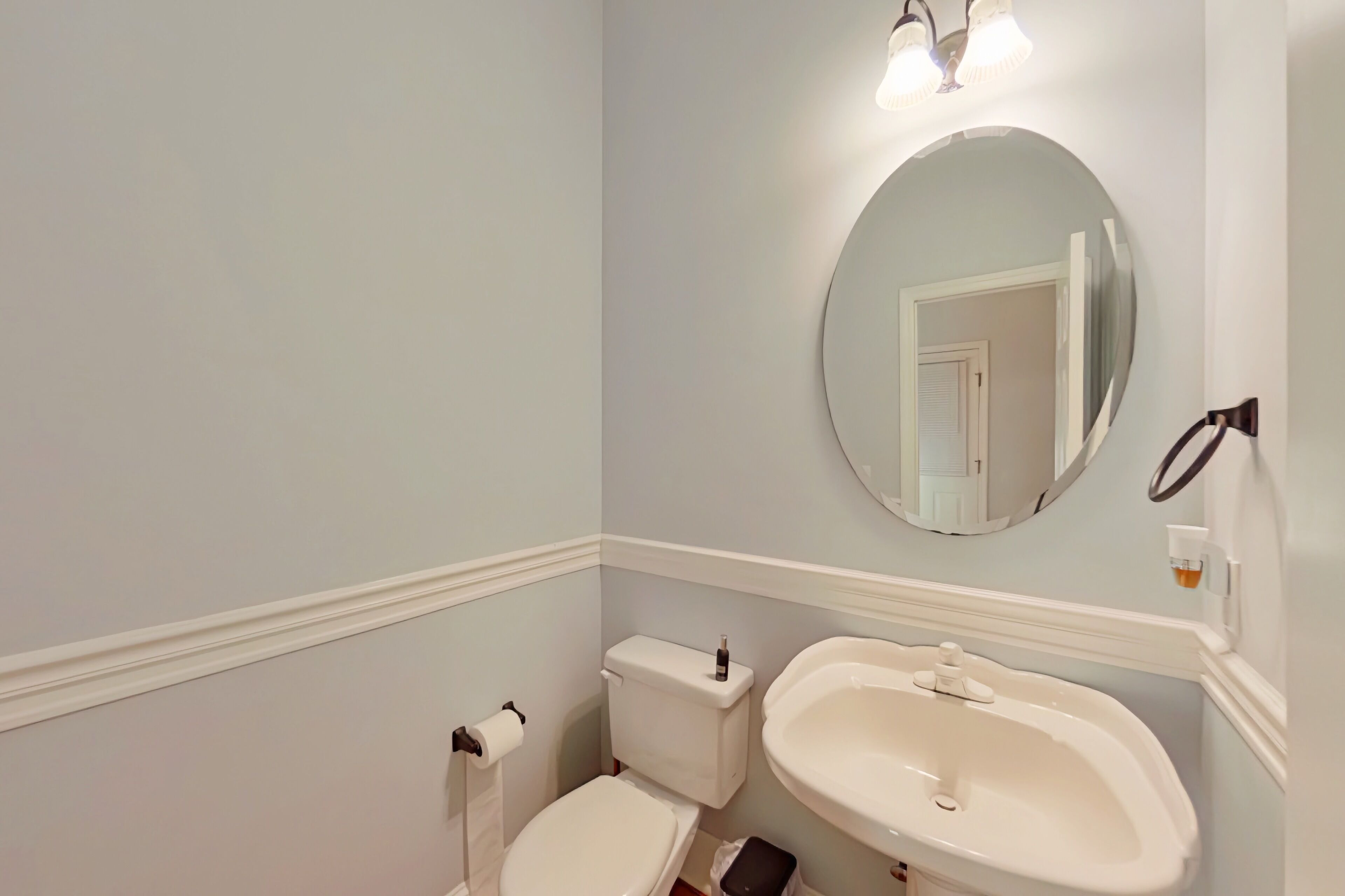A bathroom with a toilet, sink, and mirror.