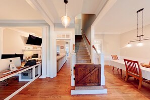 Ein großzügiger Innenraum mit einer Holztreppe, einem Essbereich und einem Home-Office-Arbeitsplatz.