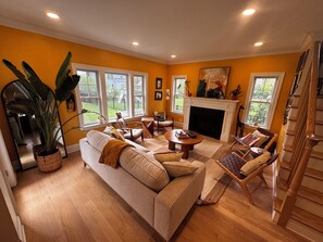Ein Wohnzimmer mit Kamin, großen Fenstern und einer Treppe.