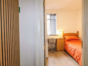 A bedroom with a bed, desk, chair, and a window with curtains. - 57 Abbey Street (Nottingham)