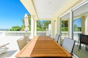 A wooden table with chairs on a balcony with a view of the sea. - Villa Montinho da Serra, Monchique (Monchique)