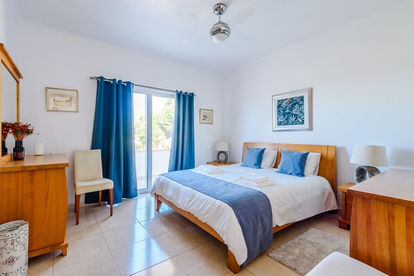 A bedroom with a bed, a chair, a desk, a ceiling fan, and a window with curtains. - Villa Montinho da Serra, Monchique (Monchique)