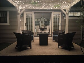 An outdoor patio with wicker furniture, a table, and string lights.