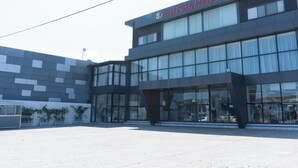Un edificio moderno con un cartello che riporta 'SILICON HEIGHTS'. Presenta ampie finestre, un tetto piano e un'area pavimentata.