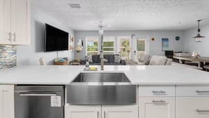 Una cocina moderna con una isla central, electrodomésticos de acero inoxidable y un televisor de pantalla plana.