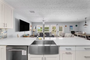 A modern kitchen with a central island, stainless steel appliances, and a flat-screen TV. - Panama Beach Getaway (Panama City Beach)