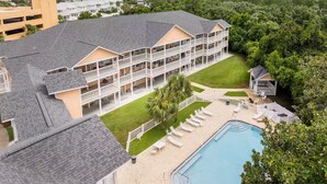 Un hotel de varios pisos con balcones, piscina y jardín.