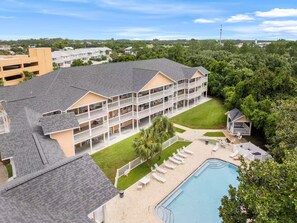 A multi-story hotel with balconies, a swimming pool, and a lawn area. - Panama Beach Getaway (Panama City Beach)