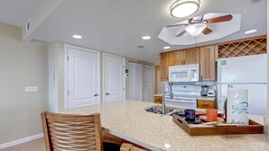 A kitchen with a central island, a ceiling fan, and built-in appliances. - Cozy 2-bedroom apartment in charming Cocoa Beach with AC (Cocoa Beach)