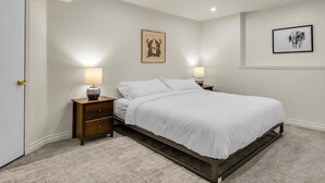 Een slaapkamer met een bed, twee nachtkastjes, een deur en twee wandlampen.