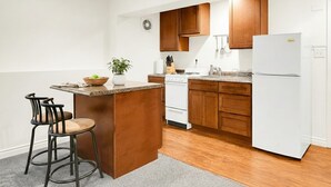 Een moderne keuken met houten kastjes, een witte koelkast en een centraal eiland met barstoelen.
