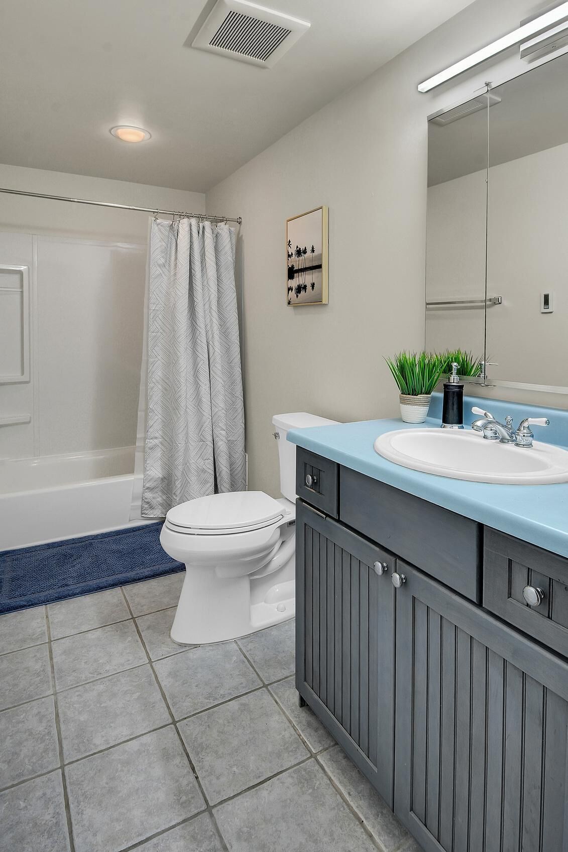 A bathroom with a bathtub, toilet, vanity with a sink, and a mirror.