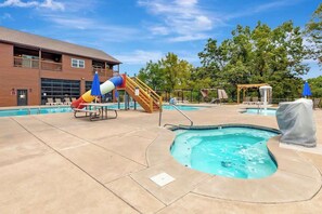 A pool area with a slide, lounge chairs, and a building with a balcony. - SDC | Lake View | Pools·Hot Tub·Sauna | Theater Rm (MARVEL CAV PK)