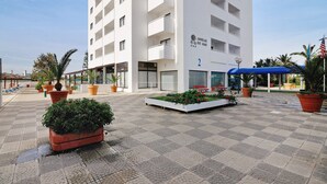 Un hotel de diseño moderno, con una entrada amplia, un área de estar exterior cubierta y plantas en macetas.