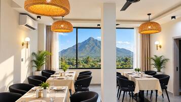 A dining area with tables set for a meal, large windows with a mountain view, and hanging wicker lamps.