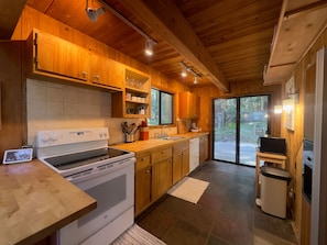 A modern kitchen with wooden cabinets, a built-in oven, a sink, and a refrigerator. - Sea Pony | Ocean Views, Hot Tub, Family Friendly (Sea Ranch)