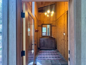 A wooden interior hallway with a mirror, chandelier, and patterned rug. - Sea Pony | Ocean Views, Hot Tub, Family Friendly (Sea Ranch)