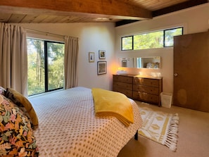 A bedroom with a bed, a dresser, a mirror, and a window with curtains. - Sea Pony | Ocean Views, Hot Tub, Family Friendly (Sea Ranch)