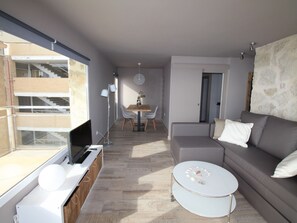 A modern living room with a flat-screen TV, a sofa, a coffee table, and a dining area with a table and chairs. - APARTAMENTO VORAMAR by Interhome (Alicante)