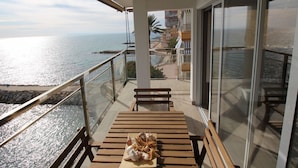A balcony with a wooden table and bench, overlooking a coastal area with buildings and a clear sky. - APARTAMENTO VORAMAR by Interhome (Alicante)