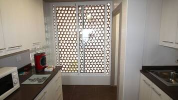 Een koelkast, een microgolfoven, een oven, kookgerei, borden en bestek