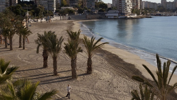 A beach with palm trees and a person walking, overlooking a cityscape with high-rise buildings. - APARTAMENTO VORAMAR by Interhome (Alicante)