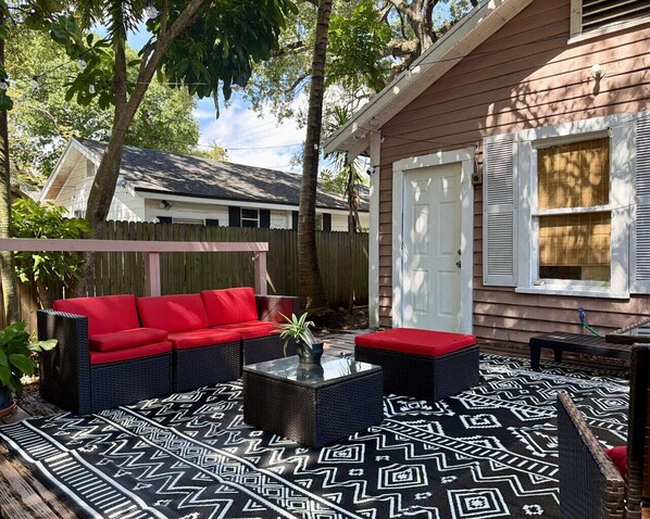 A patio with a patterned floor, a red sofa, and a small table. - The Coconut Grove Hideaway (Miami)