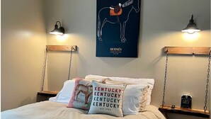 Un dormitorio con cama, almohadas, un cartel colgado de un caballo y luces fijadas a la pared.