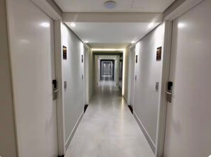 Ein langer, schmaler Hotelgang mit Türen an beiden Seiten und einem zentralen Durchgang.