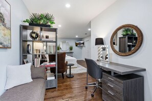 A modern living room with a sofa, a desk with drawers, a chair, a bookshelf, and a round mirror on the wall. - Upscale 4 Bd/3 Ba 5 Min to the Galleria! (Houston)