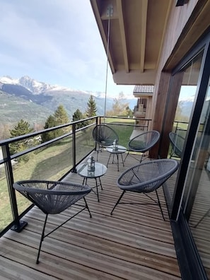 A balcony with wicker chairs and a glass table, overlooking a mountainous landscape. - Chalet, Ground floor, terrace, fireplace or stove, tv, 151m², Montalbert (Aime)