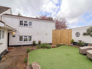 A white building with a wooden fence, a well-maintained lawn, and outdoor furniture. - The Apple Loft (Exeter)