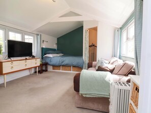A bedroom with a bed, a TV, a dresser, and a radiator. - The Apple Loft (Exeter)