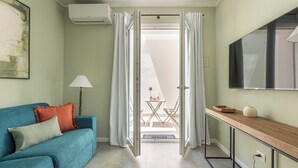 Una sala moderna con un sofá, un televisor y una puerta que da a un balcón.