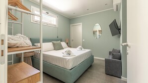 Un dormitorio con cama, zona de estar, televisión y armario.