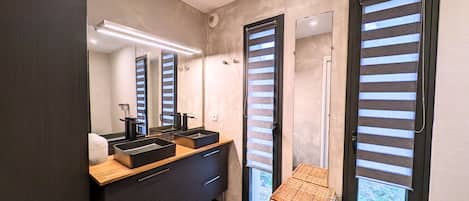 Une salle de bain moderne avec deux lavabos, un grand miroir et un panier en osier.