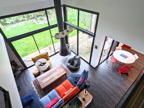 A modern interior with a large glass door leading to a garden, a cozy seating area with a sofa and chairs, a small table, and a dining table with chairs. - Bright family home between sea and Brière (Saint-André-des-Eaux)