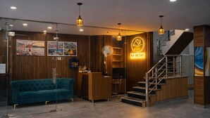 A modern interior with a reception desk, a staircase, and a blue sofa. - RNR Retreat Serenity By The Ganges (Rishikesh)
