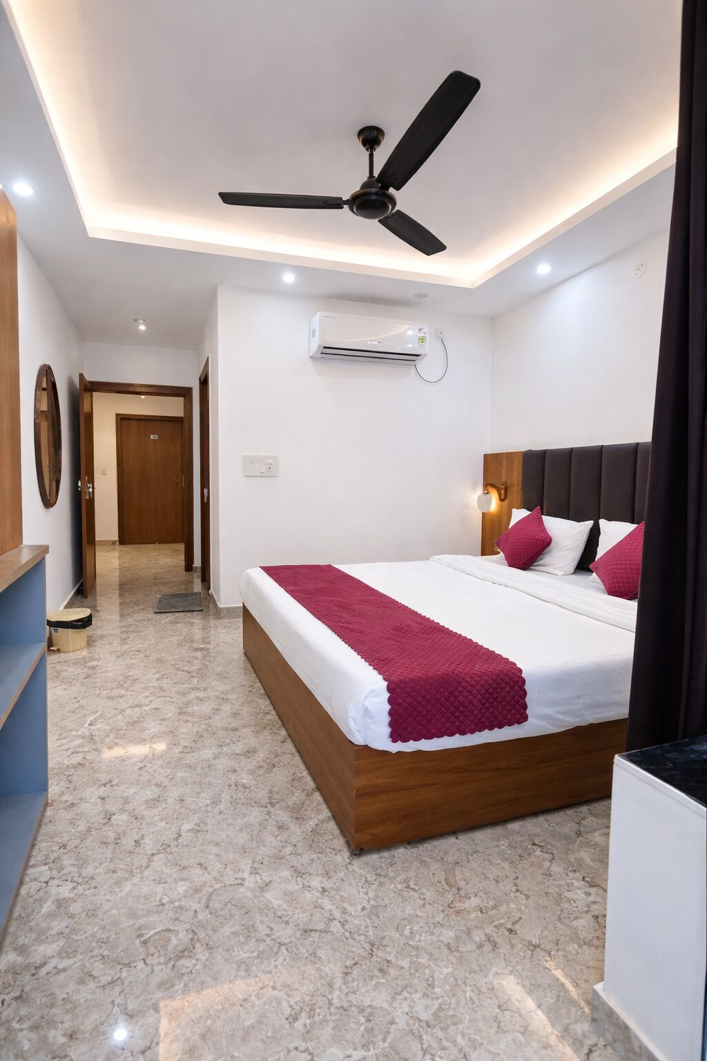 Un dormitorio con cama, ventilador de techo, aire acondicionado, cabecera de madera y piso de mármol.