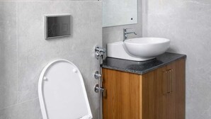 A modern bathroom with a toilet, a sink, a mirror, and a wall-mounted heater. - RNR Retreat Serenity By The Ganges (Rishikesh)