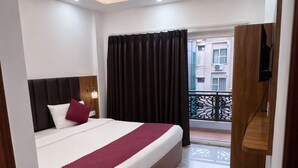 A modern hotel room with a large bed, ceiling fan, and a balcony with a view. - RNR Retreat Serenity By The Ganges (Rishikesh)