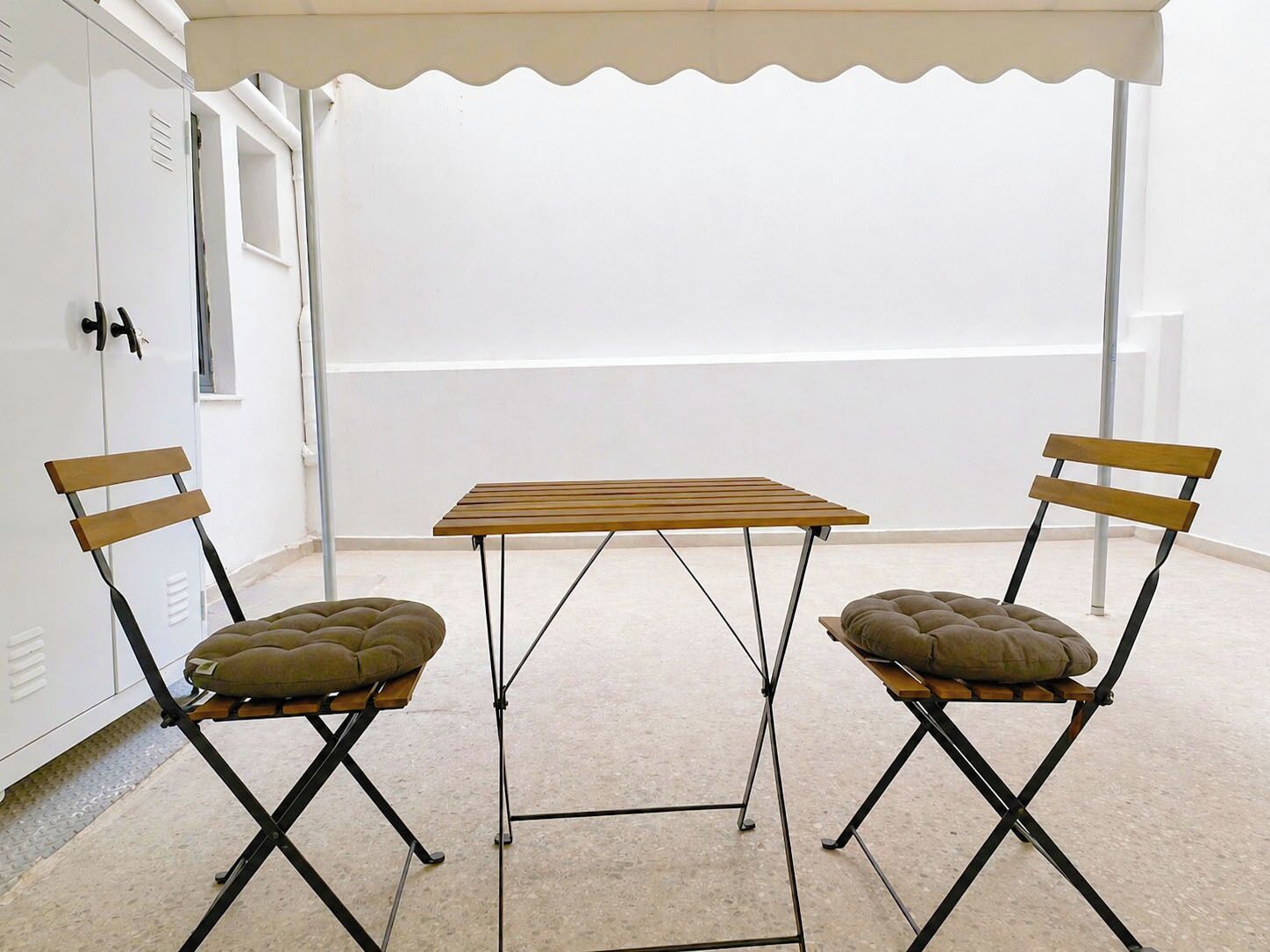 A room with a table and two chairs under a white canopy.