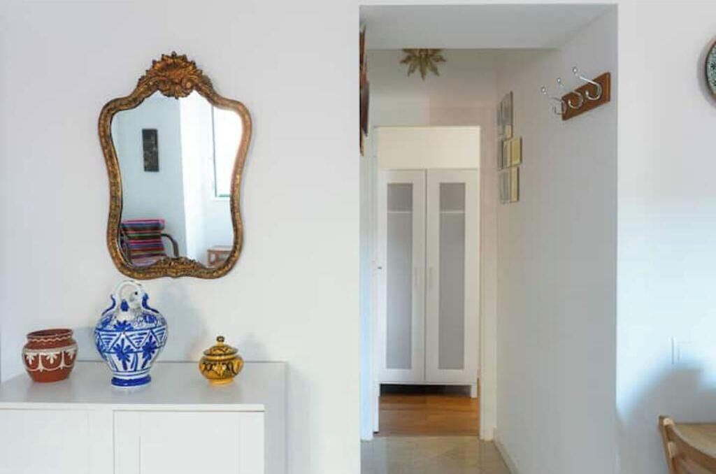 Une pièce avec une armoire blanche, un miroir et des objets de poterie décoratifs.