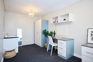 Una habitación moderna y minimalista con escritorio, silla y estantería.