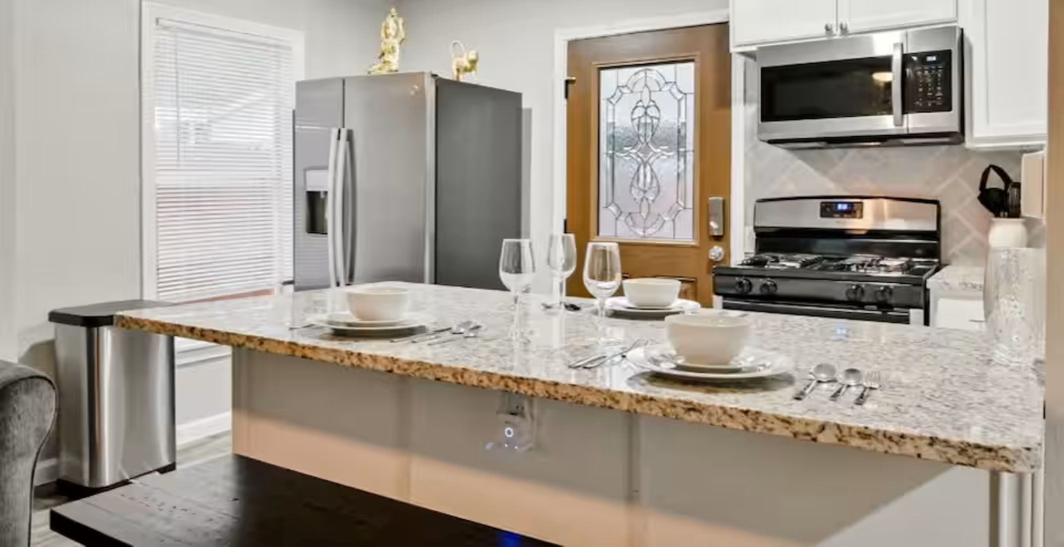 A modern kitchen with stainless steel appliances, granite countertops, and a central island with seating.