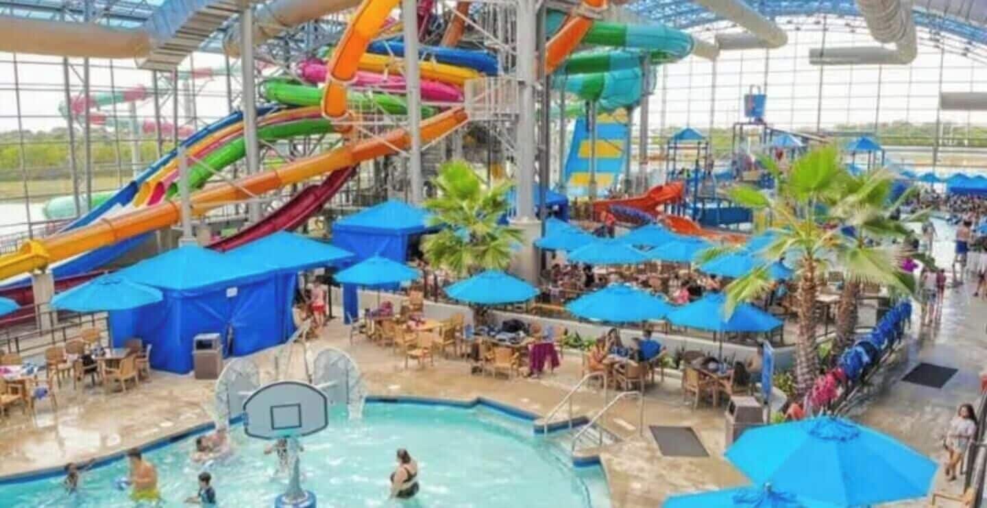 An indoor water park with multiple water slides, a pool area, and outdoor seating.
