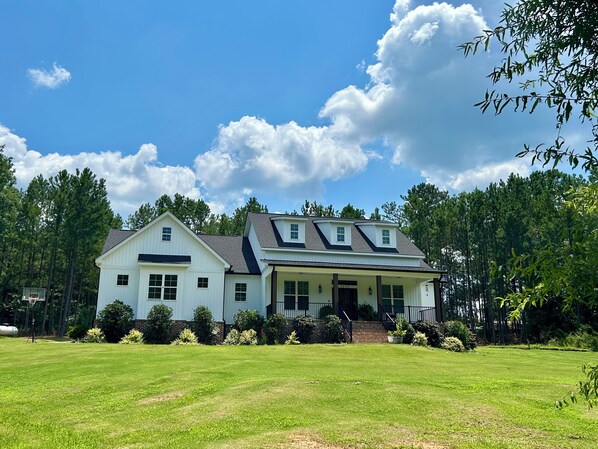 A two-story house with a front porch, a garage, and a well-maintained lawn.