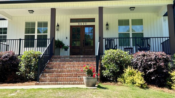 A two-story house with a front porch, a brick staircase, and a front door with the number 3177.