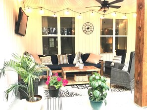 A cozy living room with a sofa, chairs, a coffee table, and potted plants.
